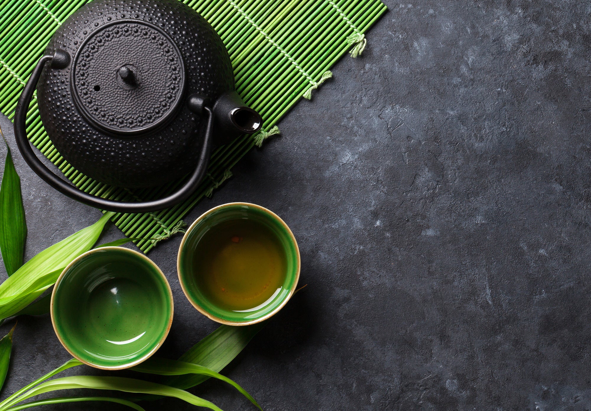 Green tea in iron cups with an iron teapot