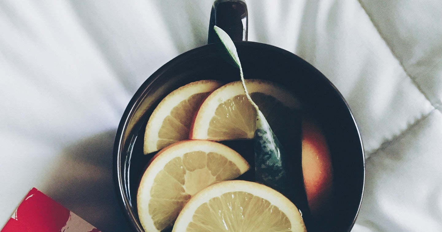 Black cup of tea on a table with slices of lemon inside