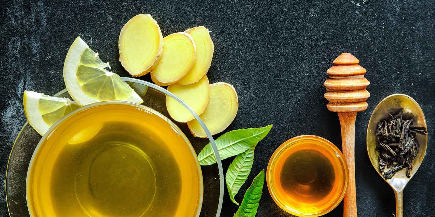 Glass cup of tea with ginger, honey and a spoon of loose tea