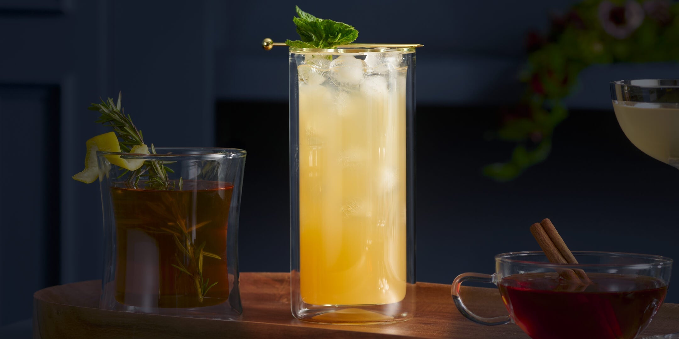 Orchid Vanilla Collins cocktail on a dark background with a sprig of mint