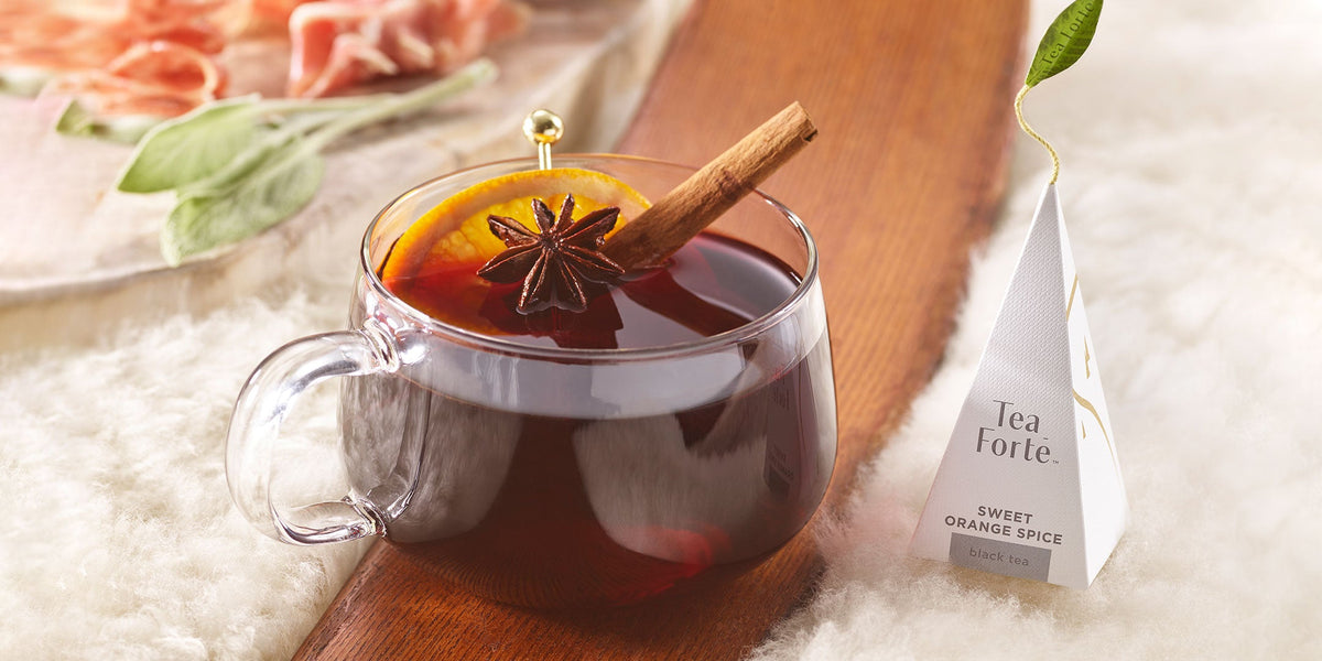 Spiced Mulled wine in glass mug on a wooden ski with sweet orange spice tea infuser 