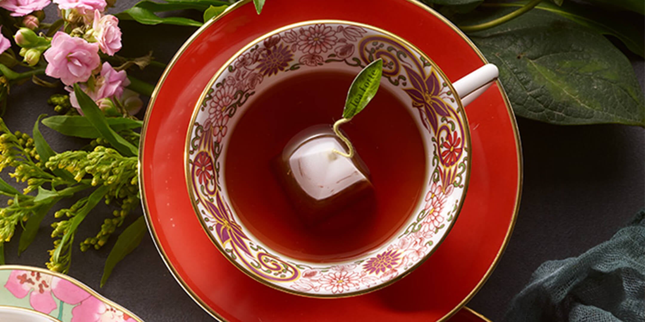 Fancy red and white tea cup with sauer full of Raspberry Nectar tea