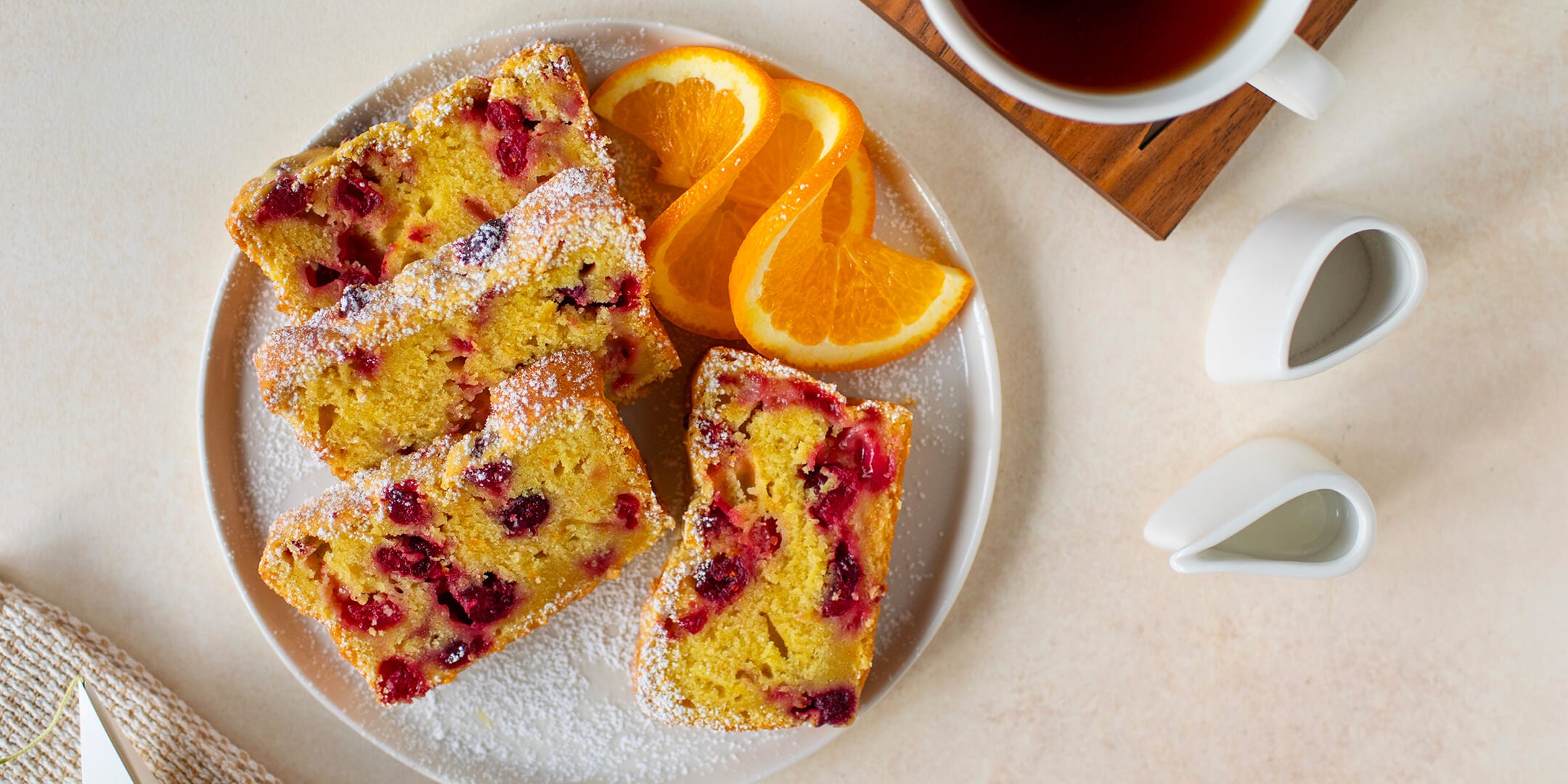 Cranberry Orange Tea Loaf, cut on a plate with an orange