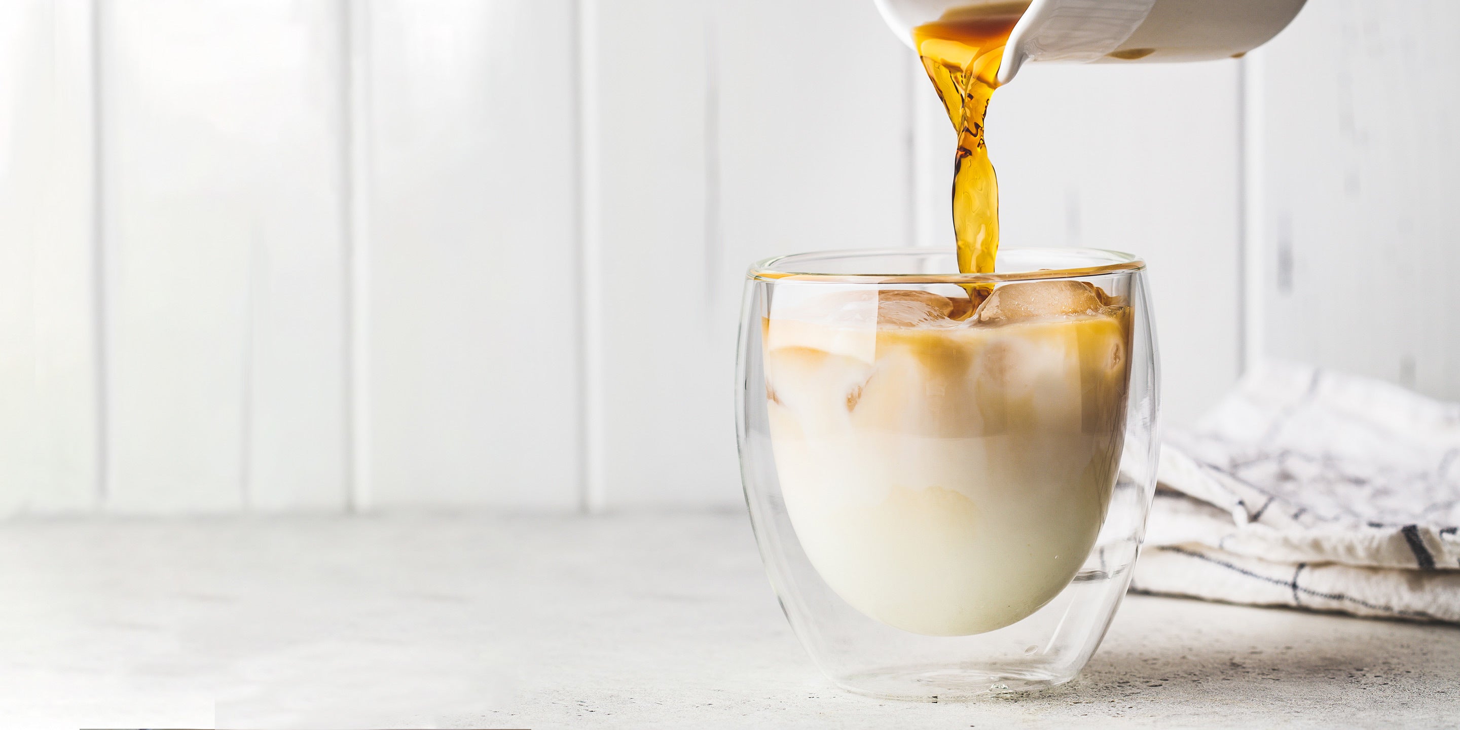 Pouring a Iced Pumpkin Spice Latte into a glass cup