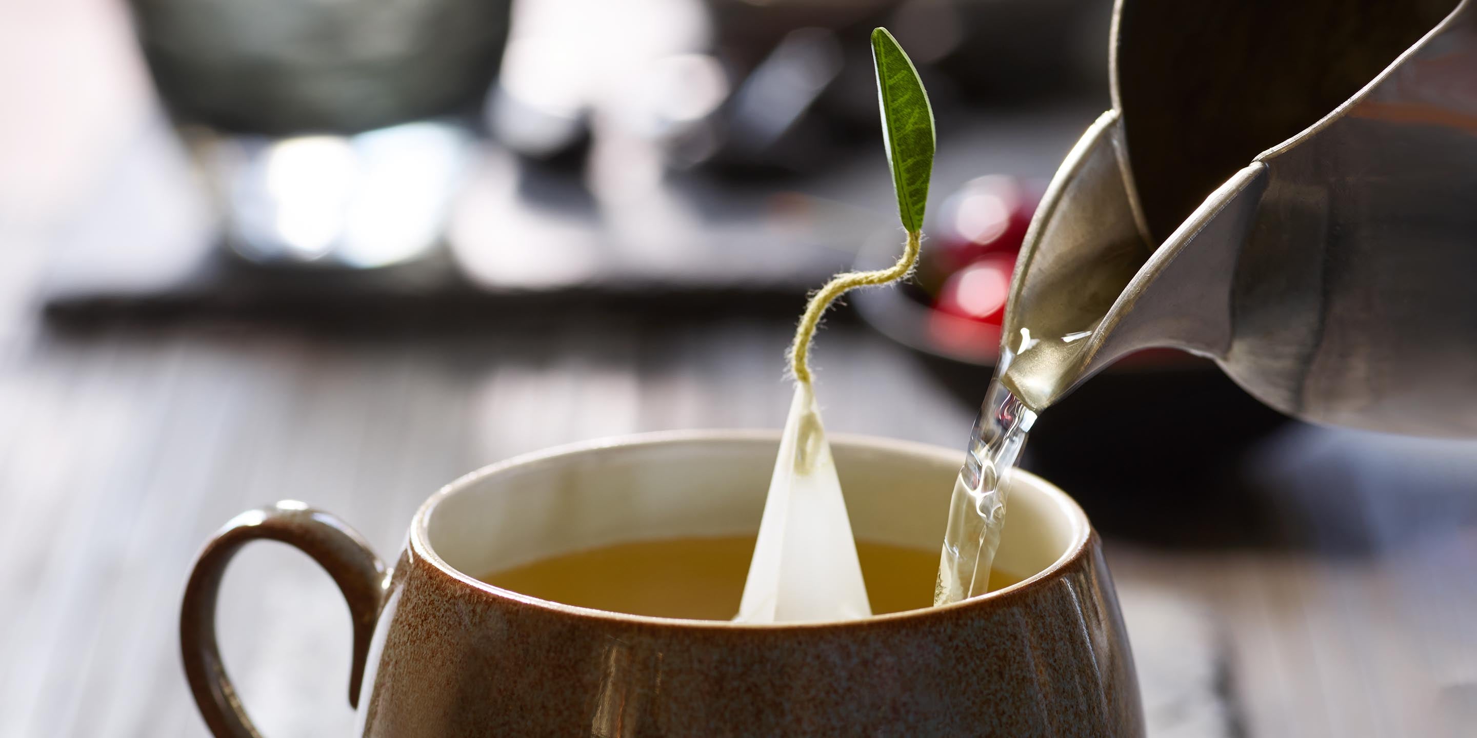 Pouring water into a teacup with a pyramid infuser inside