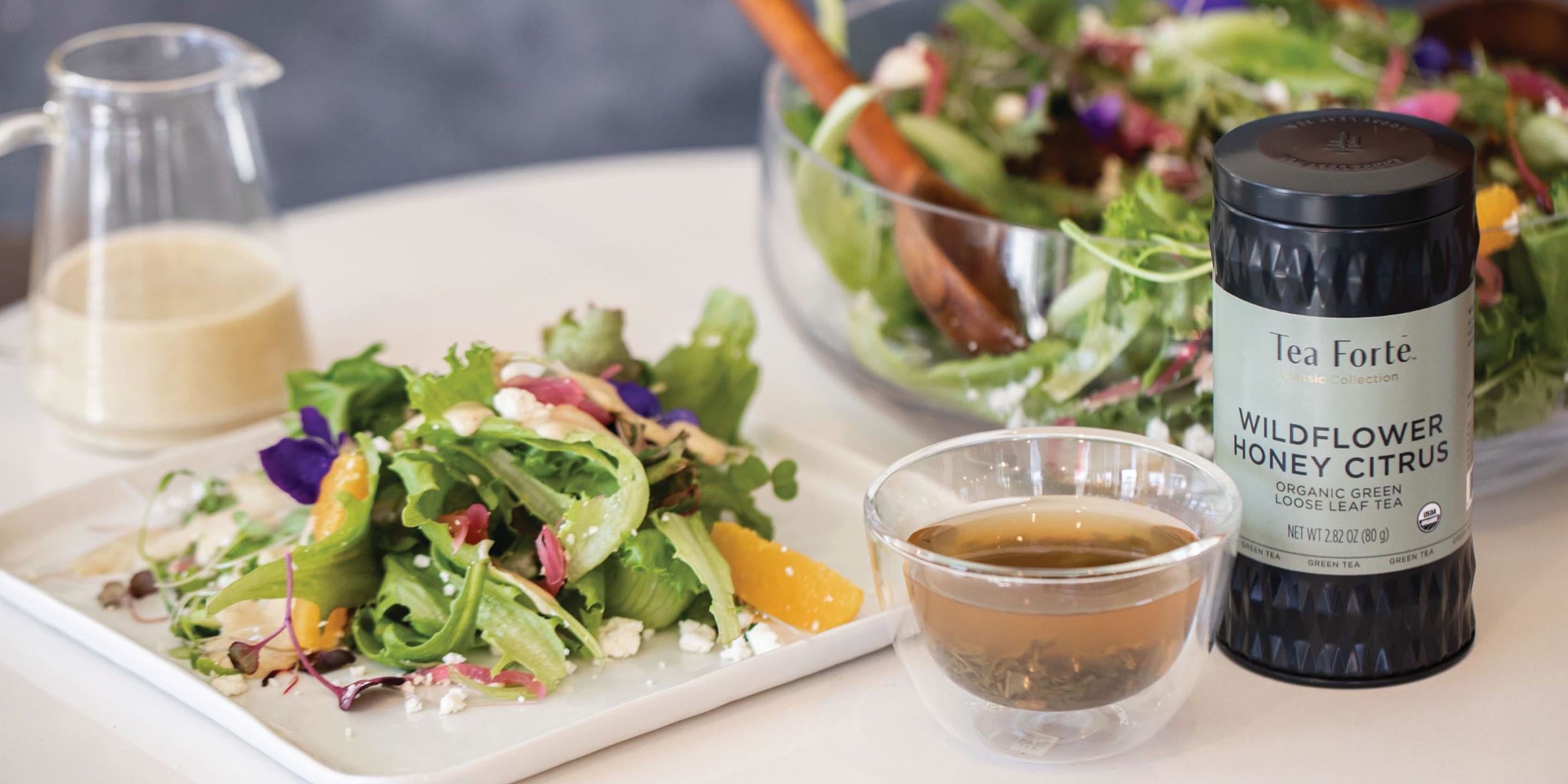 A salad with Wildflower Honey Citrus Vinaigrette and a loose tea canister