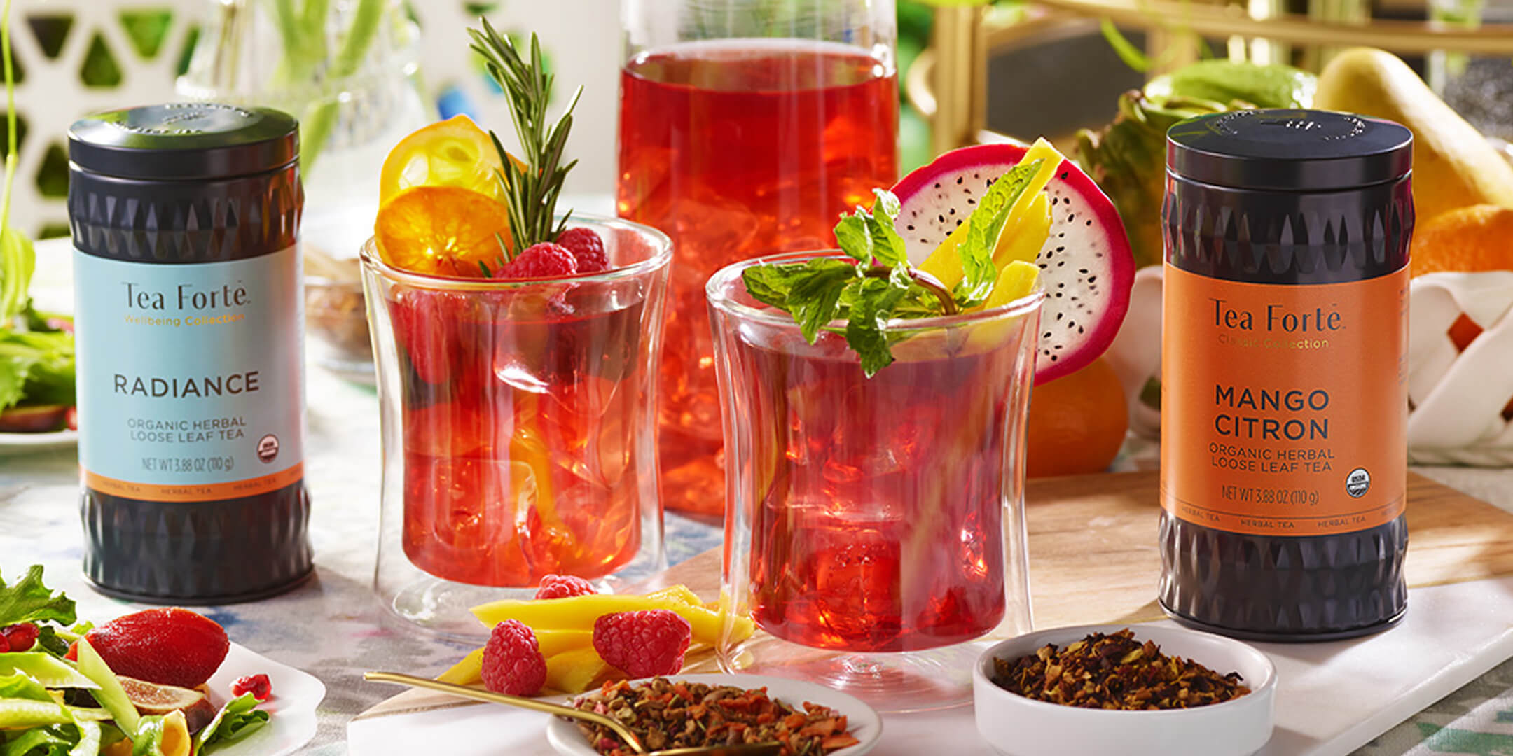 Loose tea canisters and glasses of iced tea on a table.