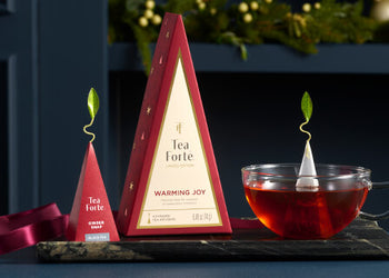 Warming Joy Petite Tea Tree of 4 teas on a table with a glass cup of tea and infuser