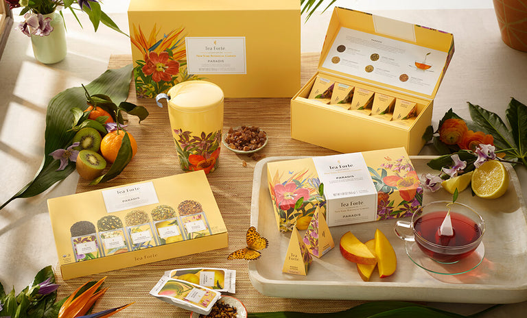 Paradis Collection on a table with fruit and butterflies