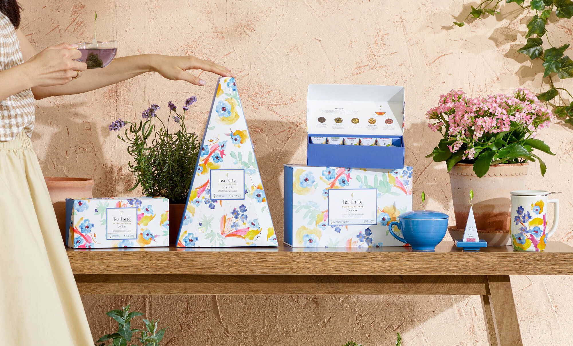 The Volaré Collection against a stucco wall and arranged on a wooden table with plants and teacups