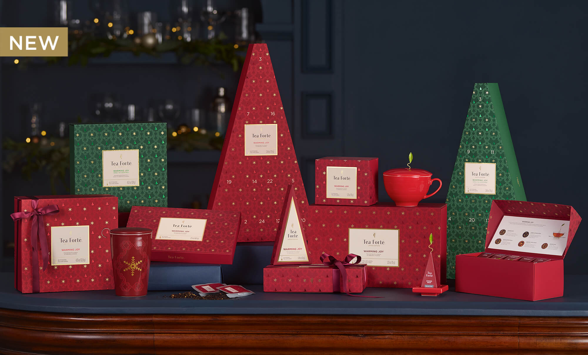 Collection of Warming Joy items in festive boxes in a dark blue room with a blurred background.