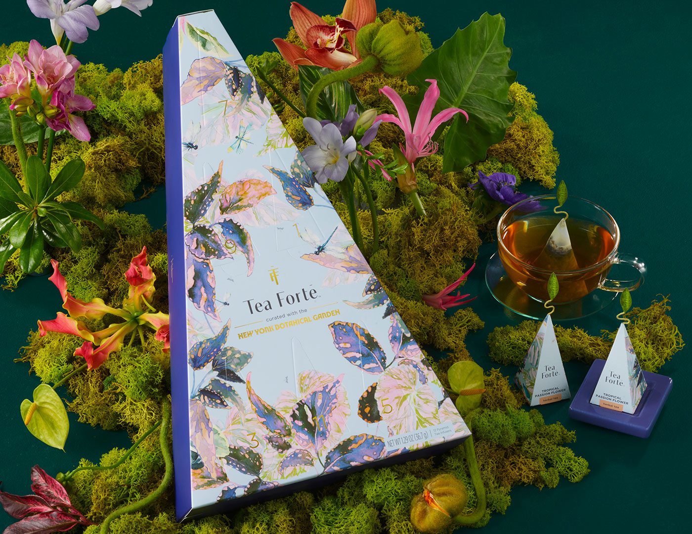 MAIN PDP | Demoiselle 12 days of Teas box with a teacup and tea infusers in a layer of moss and flowers