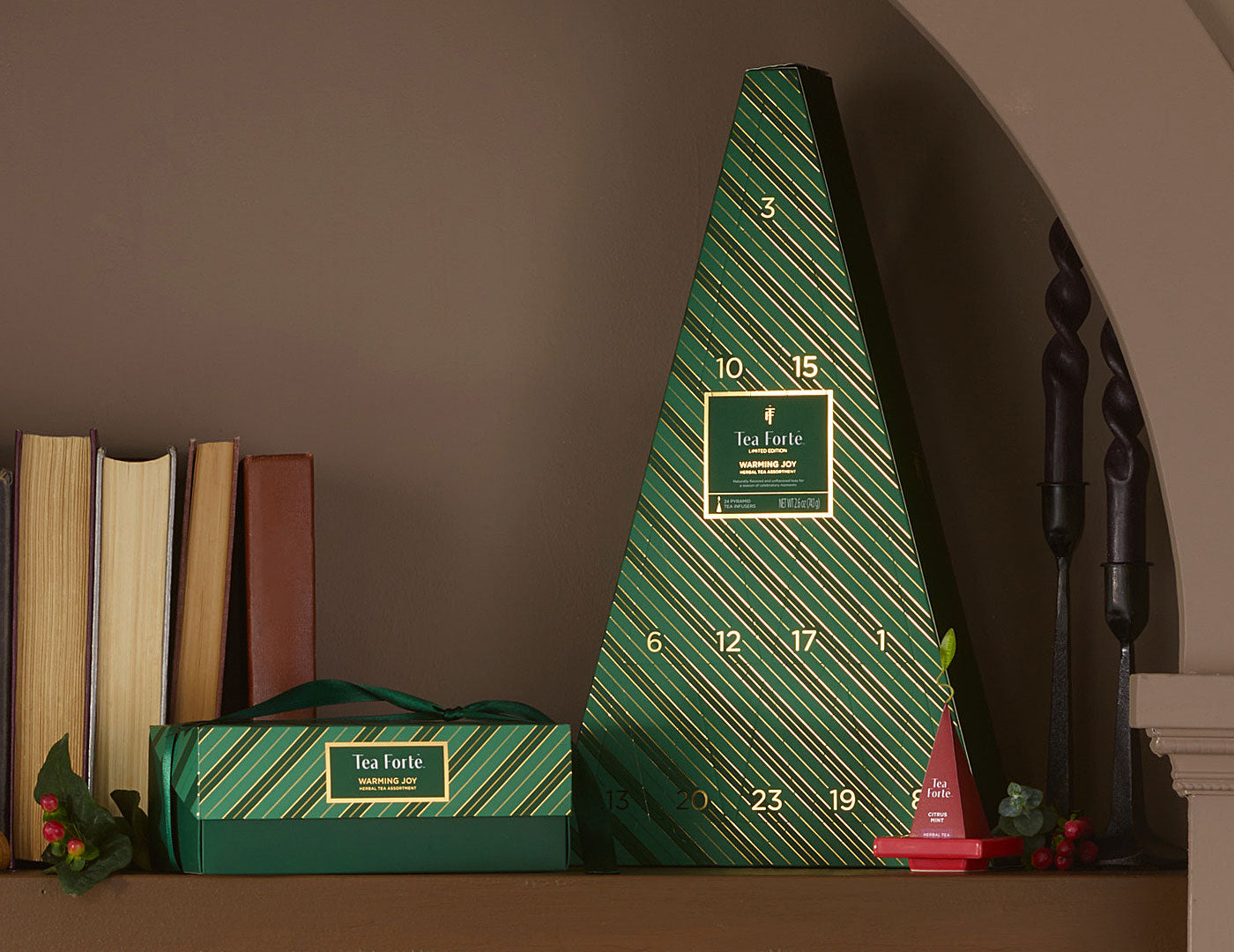 MAIN PDP | A green triangular Advent Calendar with diagonal striped pattern and gold numbers, displayed on a shelf next to a smaller matching box and decorative items.