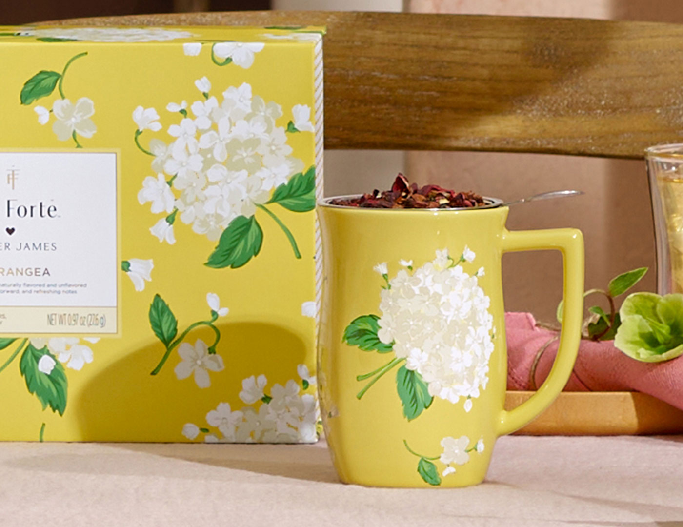 Hydrangea Fiore Steeping cup with lid off and loose tea inside with a Gift Set in the background
