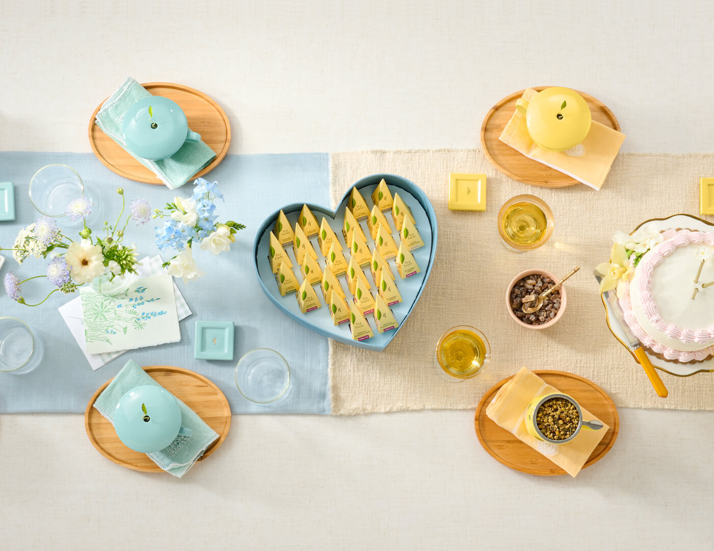 Keepsake Heart Box, Something Blue, of 26 pyramid infusers, lid open, revealing infusers, with cups of tea on a table with shower and birthday items