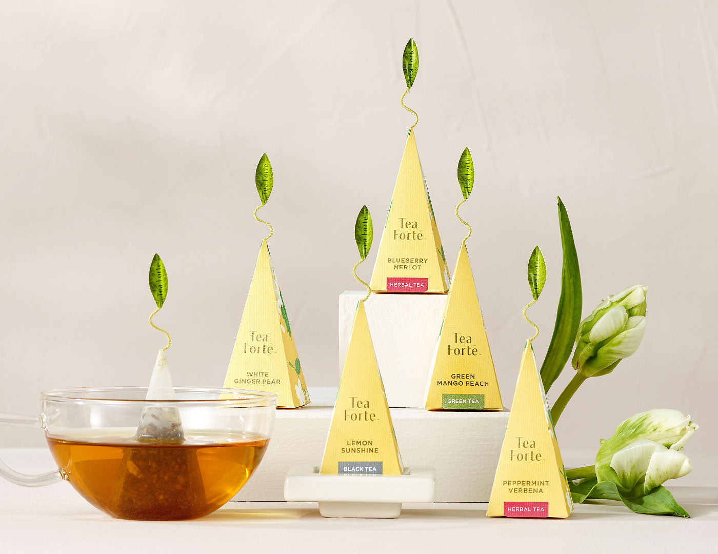 Hydrangea collection pyramid tea infusers, one of each blend on a white background with flowers and a glass of tea