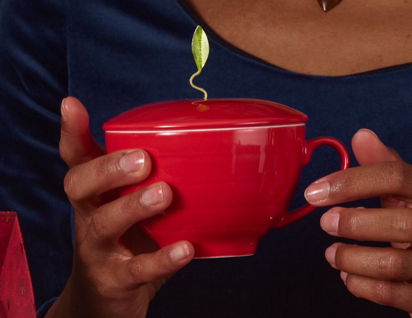Ruby Red café Cup being hand in someone hands with lid on and tea inside