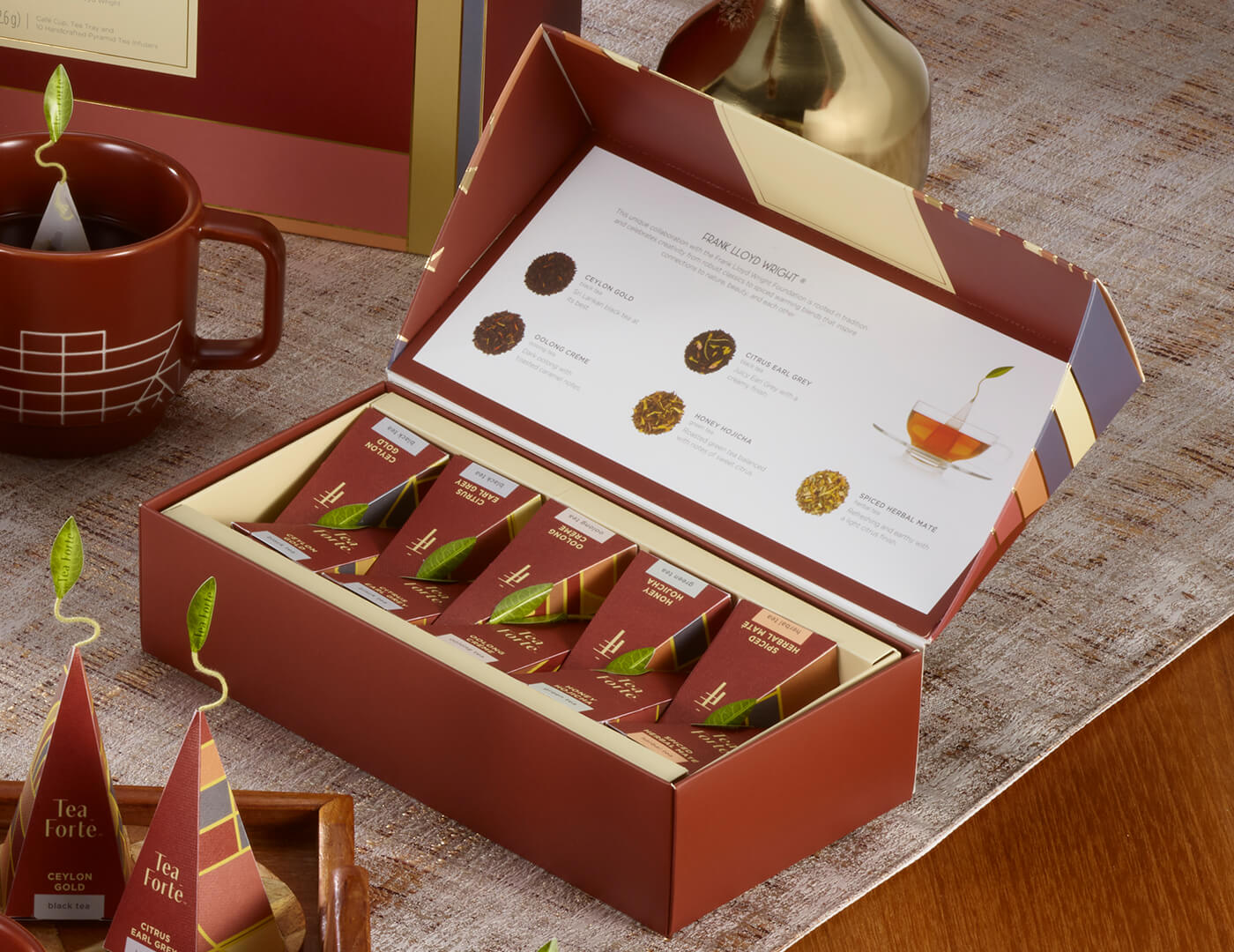 Frank Lloyd Wright Petite Presentation Box, open on table with teacup and infusers