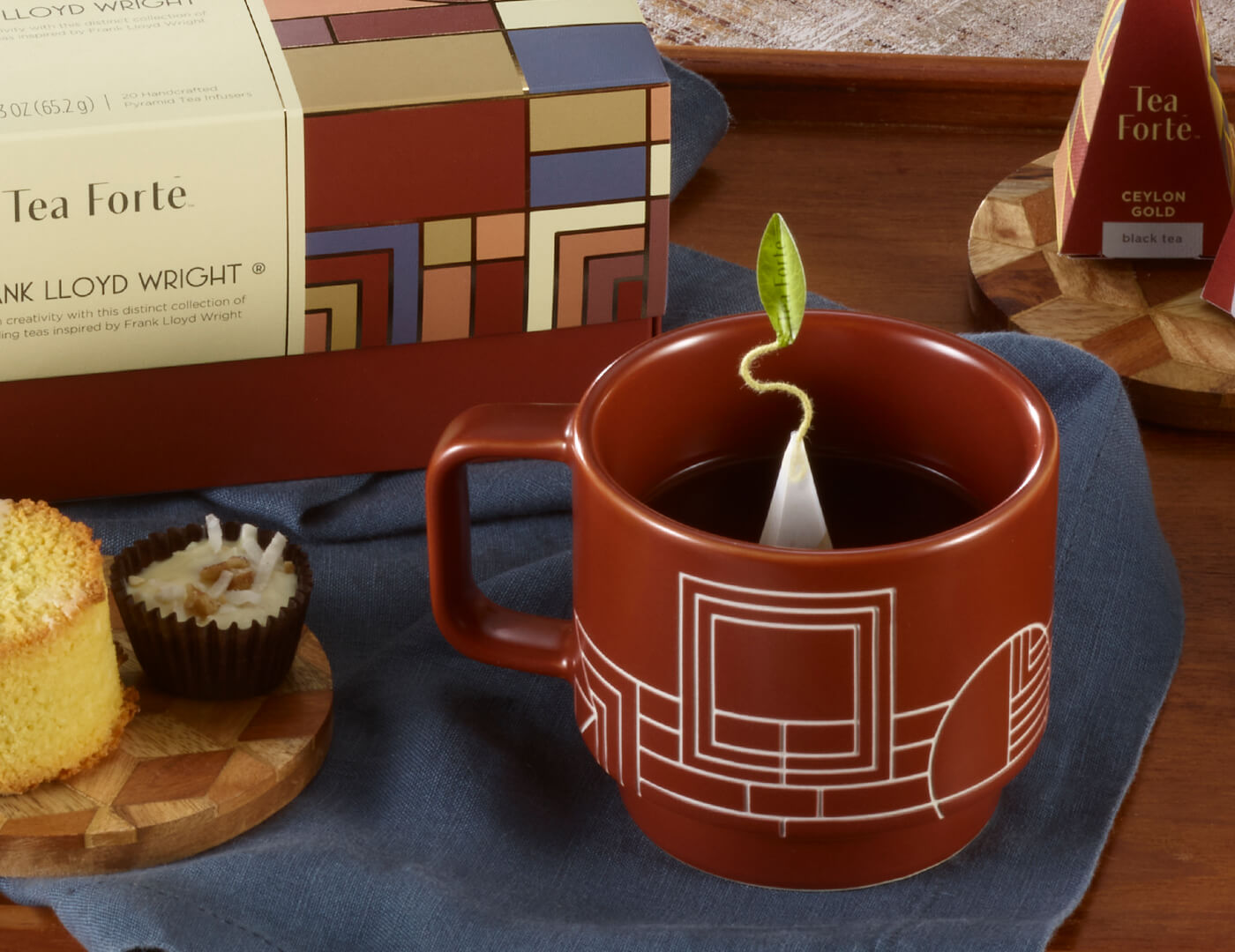Frank Lloyd Wright teacup with infuser in Terra brown on wooden table with dessert and Presentation Box