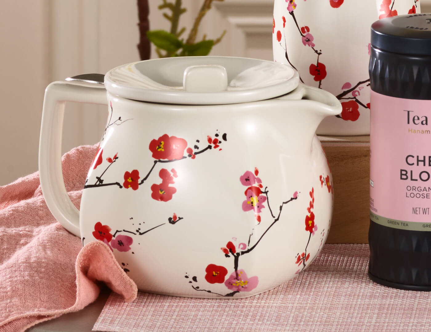 Fiore Sakura Teapot resting on table with pink cloth and Cherry Blossom loose leaf tea