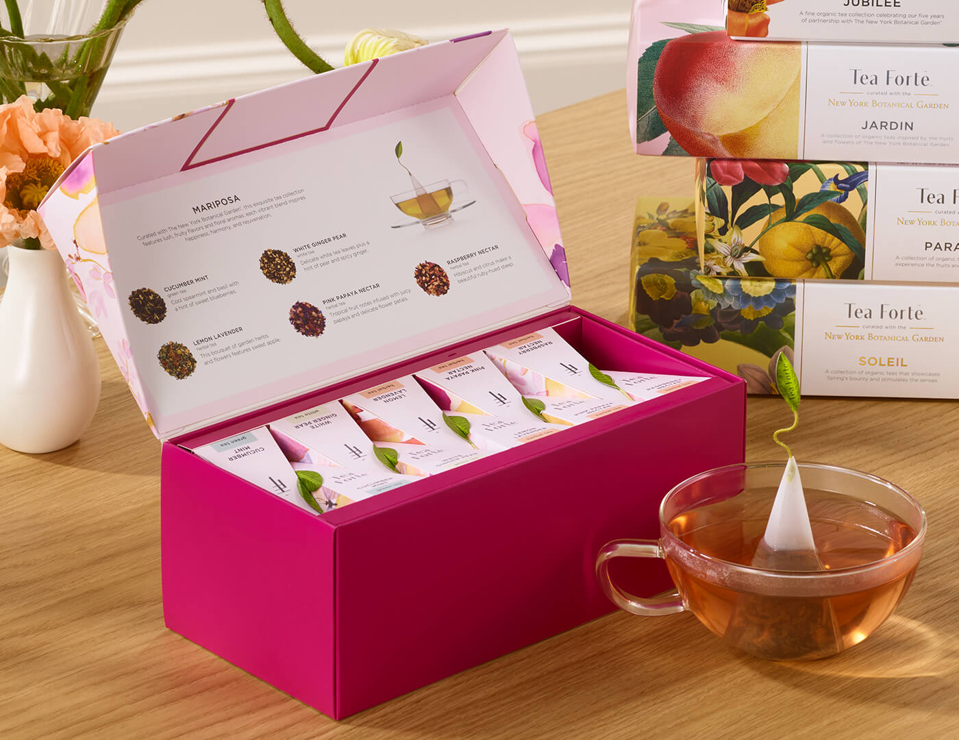 Mariposa Presentation Box of 20 pyramid tea infusers, open on a table with a glass cup of tea
