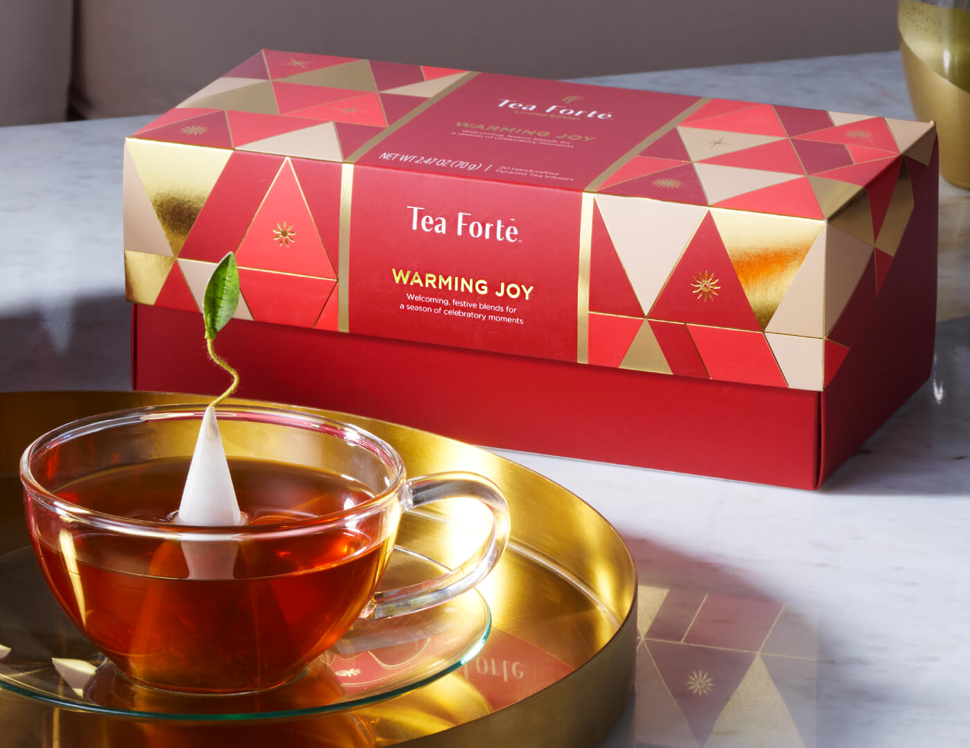 Warming Joy Presentation Box, closed with glass cup on a gold tray in front