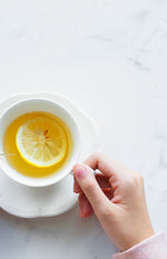 Holding a white teacup with lemon floating in it