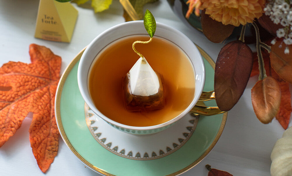 Pumpkin Spice steeping in a cup with fall leaves and flowers around it
