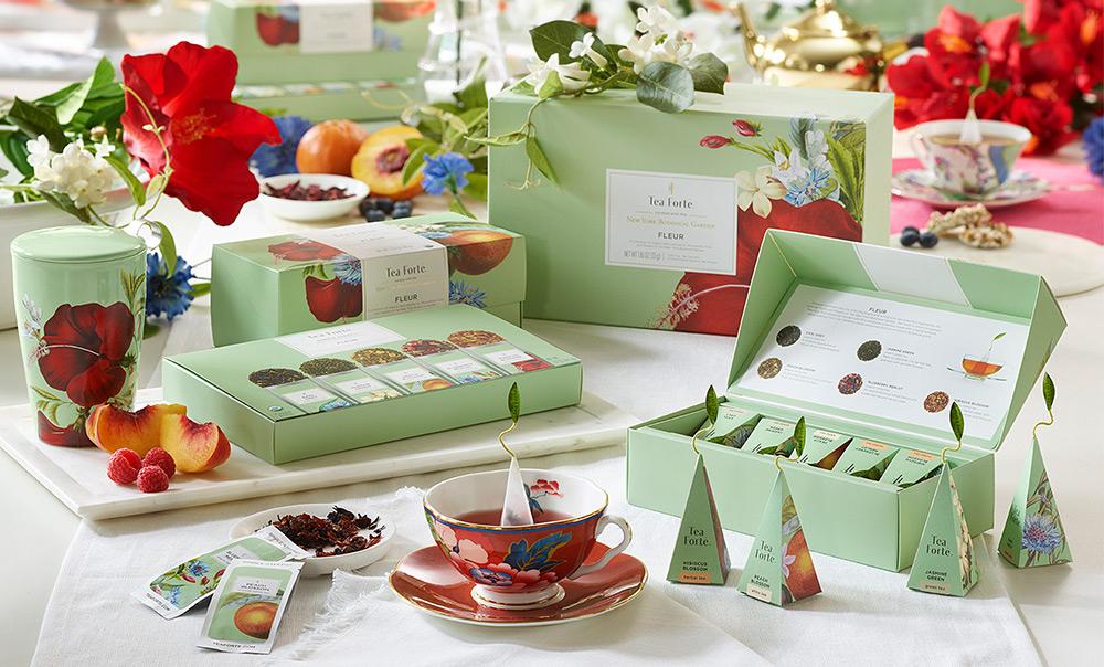 Fleur Collection on table with fresh peaches, raspberries and flowers in the background