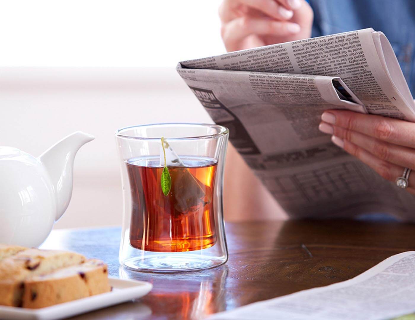 Poom cup with infuser at breakfast, reading newspaper