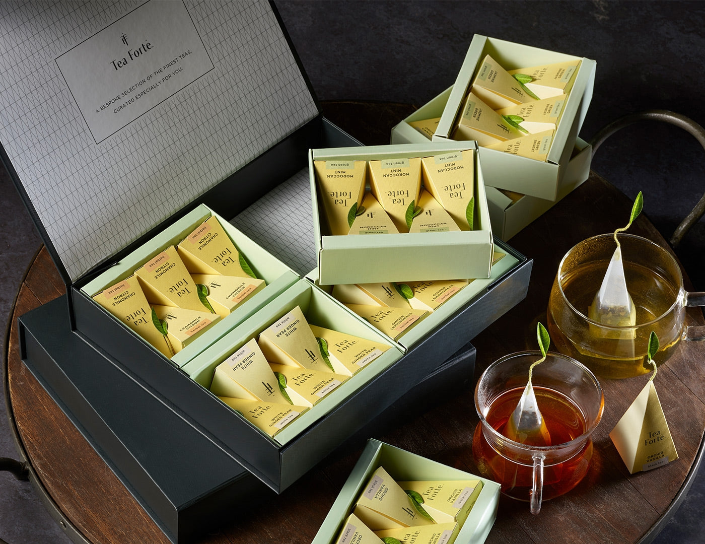 Tea Forté Select Box of 20 pyramid tea infusers, open on a wooden tray with glass teacups