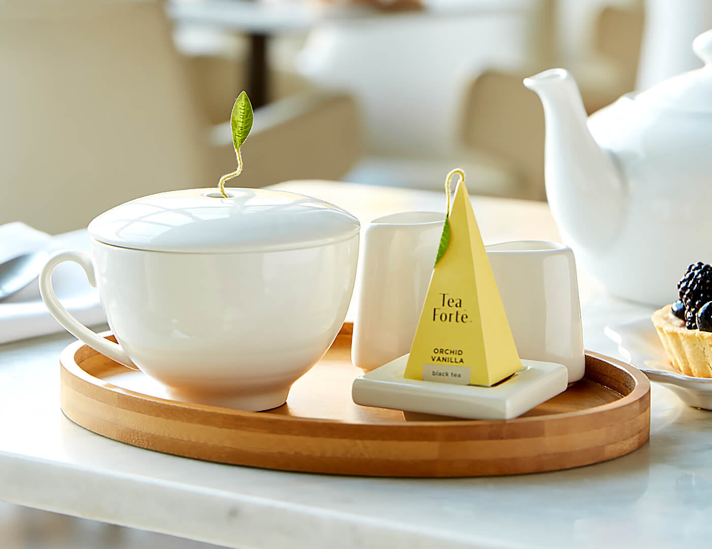 Café Cup in Bone White in a café setting on a Oval Bamboo Tray with infuser, Tea Tray and Sugar & Creamer.